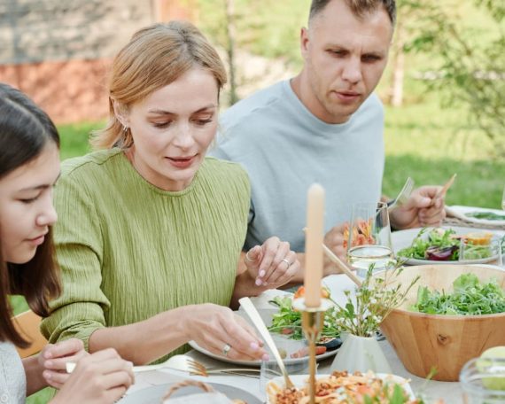 A family shares a meal outdoors, enjoying fresh and vibrant salads.
